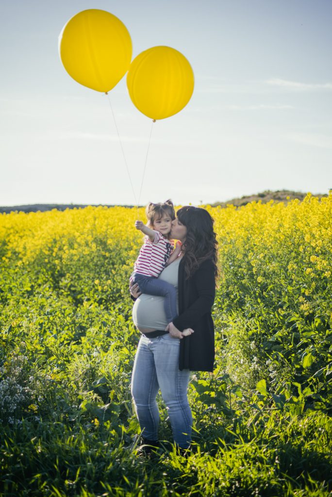 Mamá y bebé en un campo de flores amarillas de colza